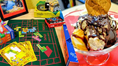 Board game pieces on table; ice cream sundae nearby.