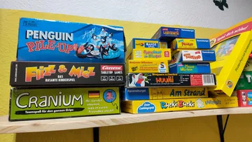Board games stacked on a shelf.