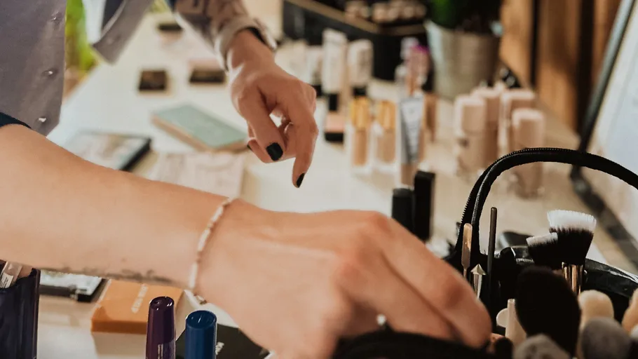 Hands arranging makeup tools on a table.