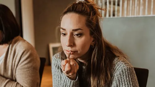 Woman applying lipstick in indoor setting.