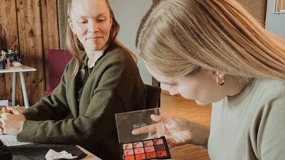 Zwei Frauen besprechen Schminkpalette drinnen.