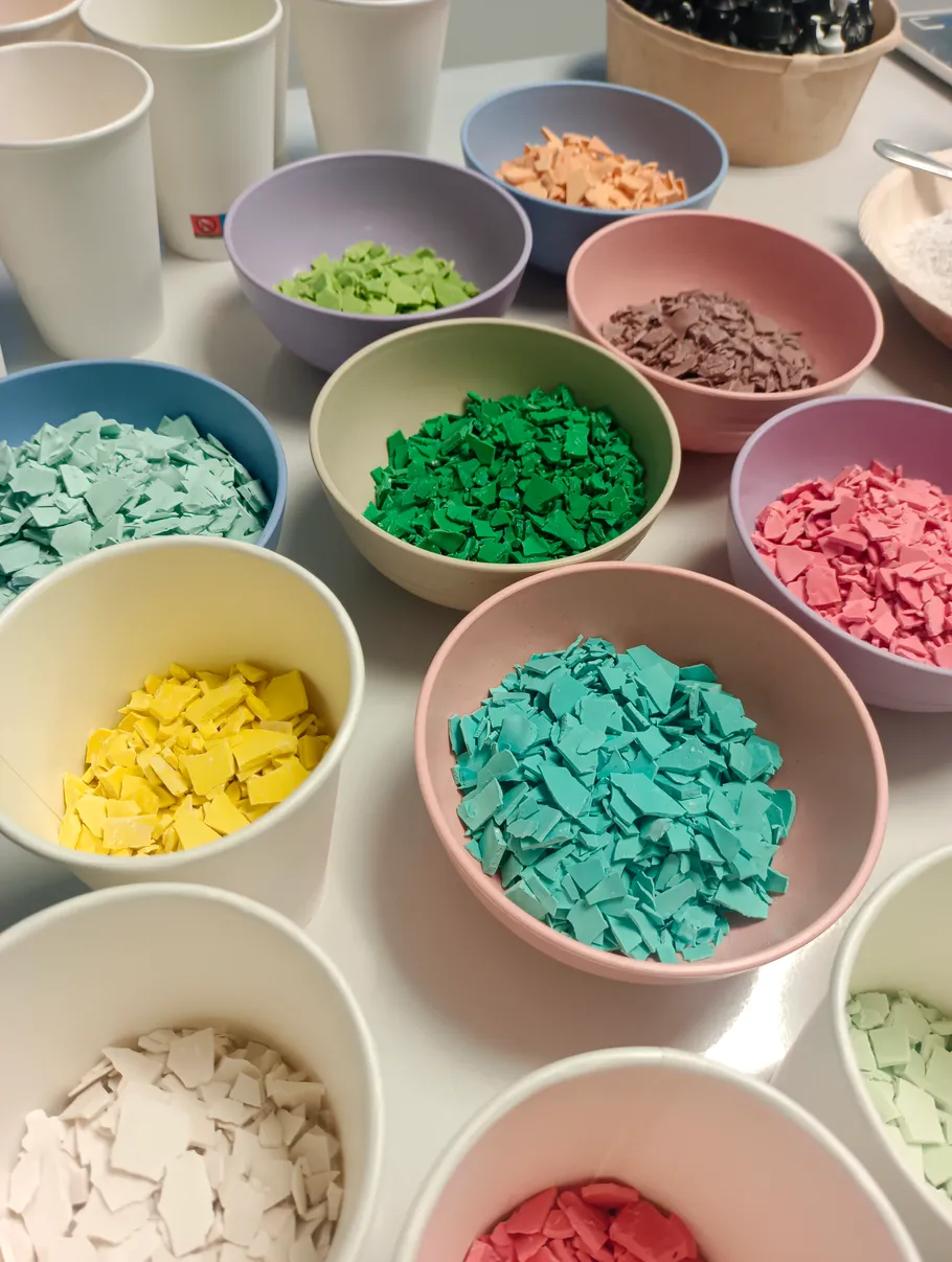 Bunte Plastikflocken in Schüsseln auf einem Tisch.