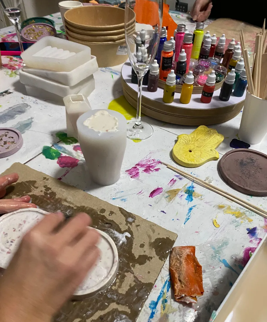 Hands crafting with molds on colorful table.