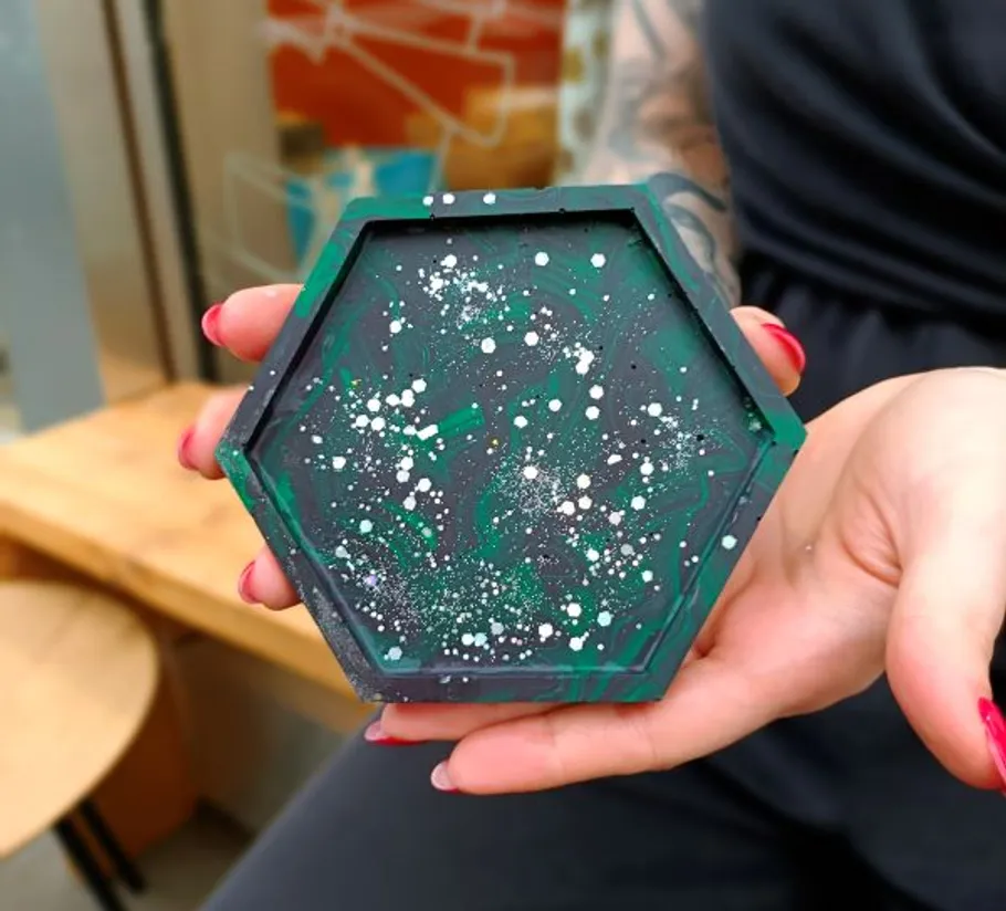 Hexagonal coaster held by person outdoors.