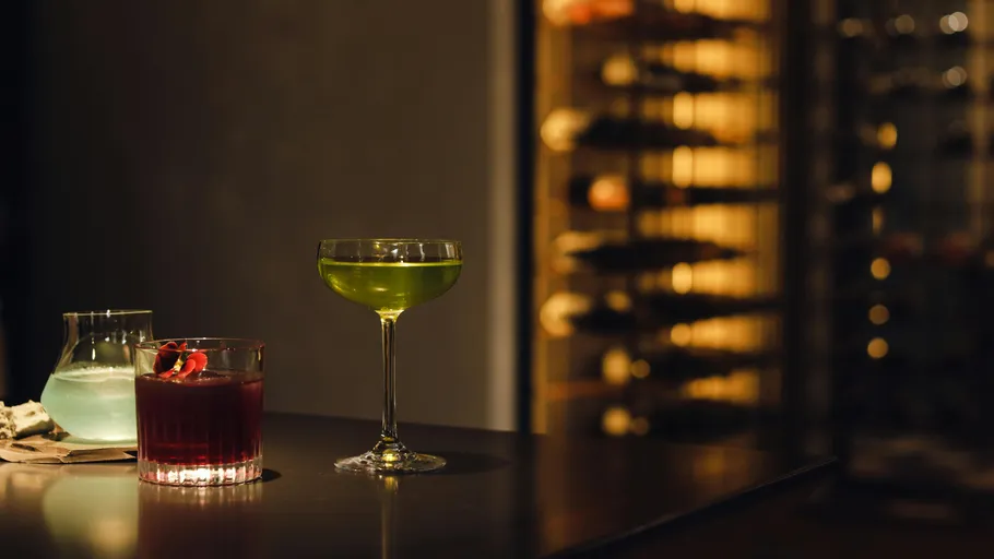 Three colorful drinks on a dimly lit bar.