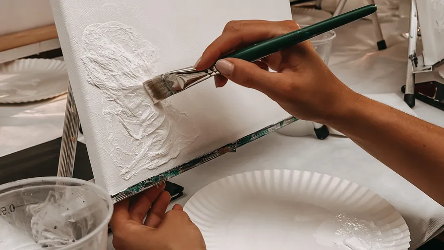 Hand painting textured canvas with brush in studio.