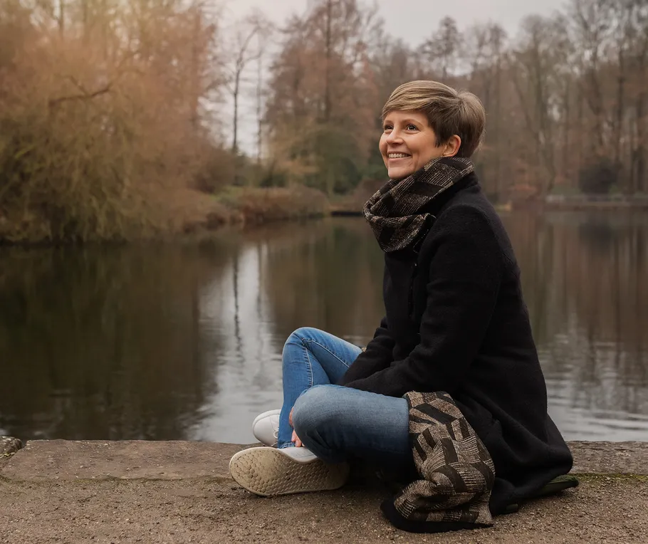 Woman sitting by a lake in a park.