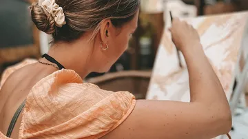 Woman painting on canvas outdoors.
