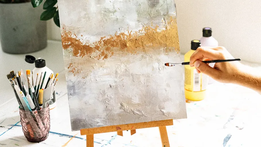Person painting abstract art on small canvas.