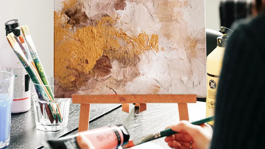 Abstract painting on easel, artist painting nearby.