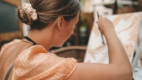 Woman painting on canvas indoors.