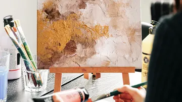 Canvas painting on easel with art supplies.