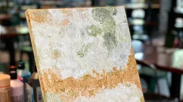 Abstraktes Gemälde mit goldenen und weißen Texturen.