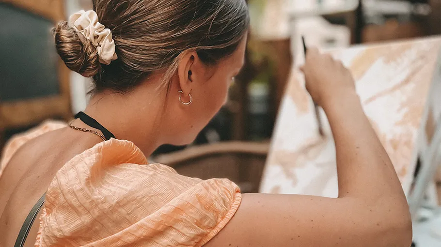 Woman painting on canvas outdoors.