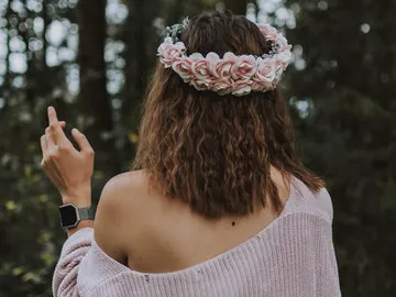 Frau mit Rosenkranz zeigt Finger im Wald.