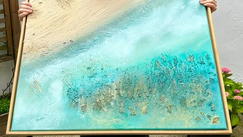 Hand hält abstraktes Strandgemälde draußen.