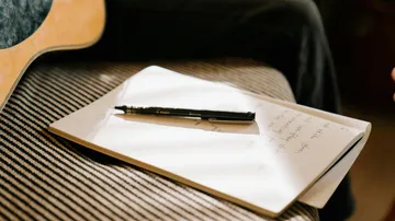 Notizbuch und Stift auf gestreiftem Sofa.