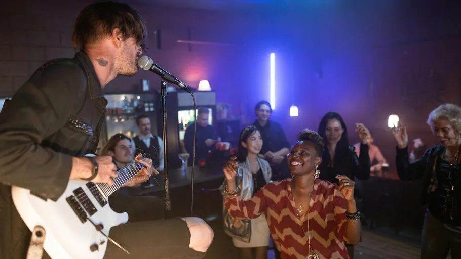 Musician singing and playing guitar in bar.
