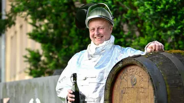 Man in protective suit holding a bottle.