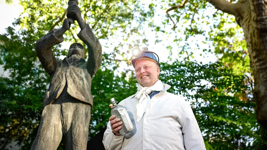 Mann in Bergwerkskleidung hält Trophäe im Freien.