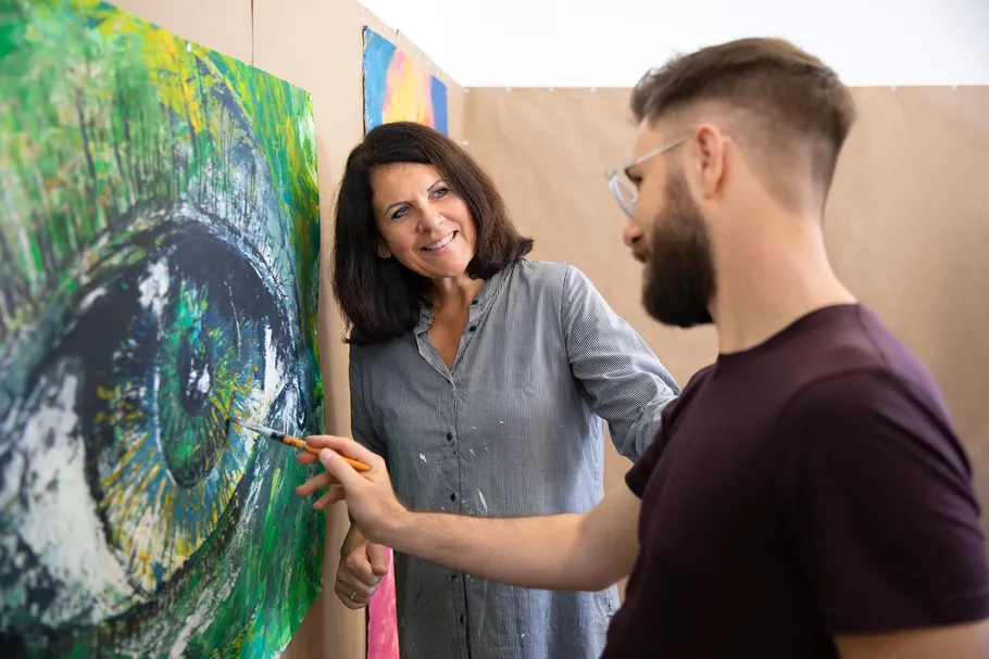 Two people discussing a colorful eye painting.