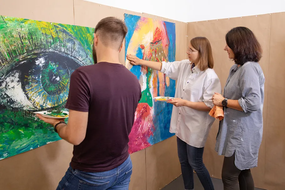 Drei Künstler malen bunte Leinwand drinnen.