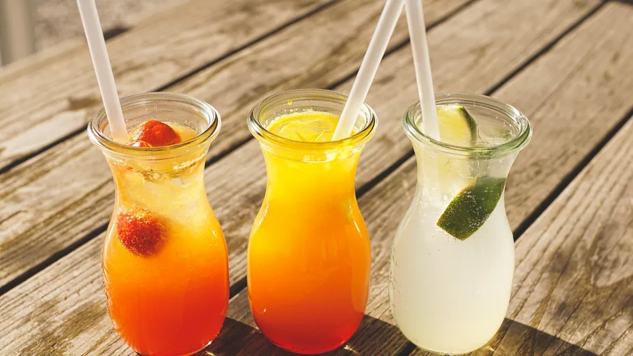 Three colorful drinks on wooden table.