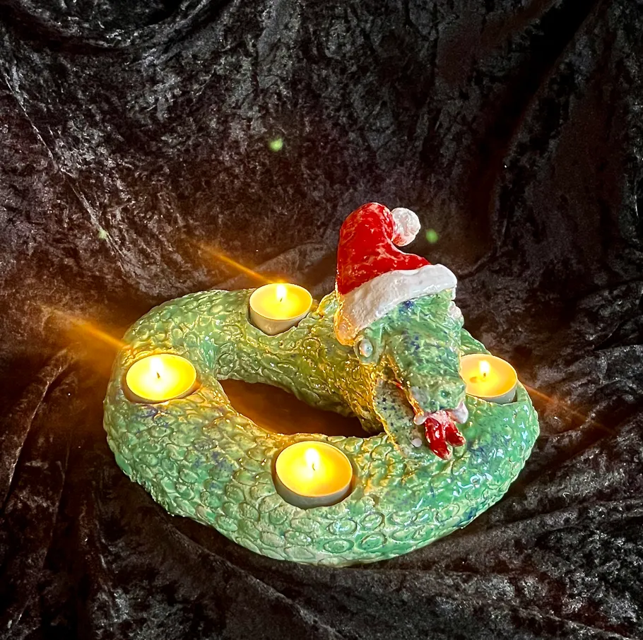 Grüner Schlangenkerzenhalter mit Weihnachtsmannmütze.