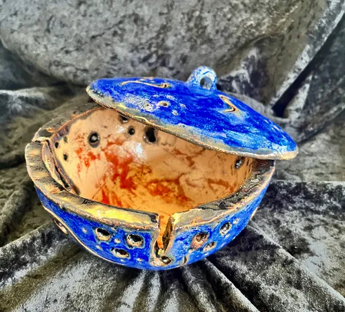 Blue ceramic pot open on velvet fabric.