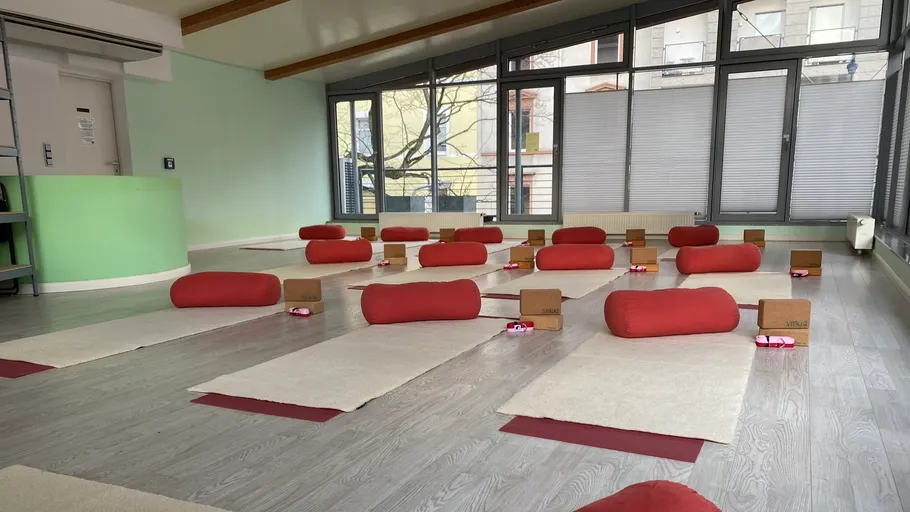Yogastudio mit Matten, Bolstern und Blöcken arrangiert.