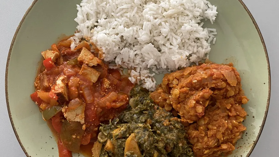 Plate with rice, stew, greens, and lentils.