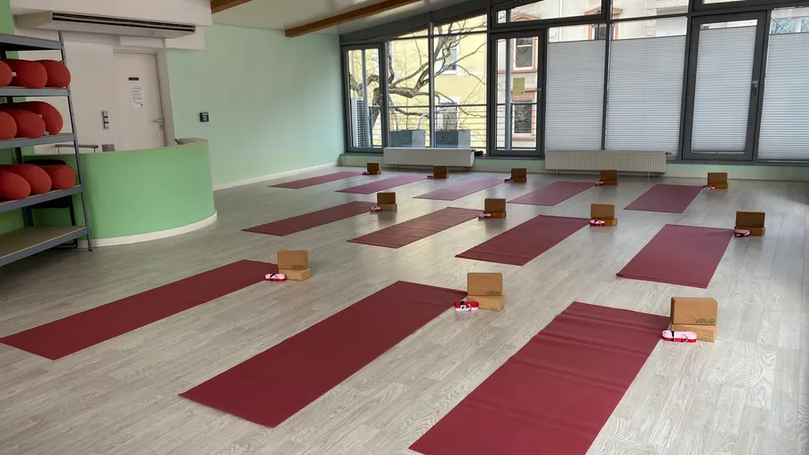 Leeres Yoga-Studio mit ordentlich angeordneten roten Matten.