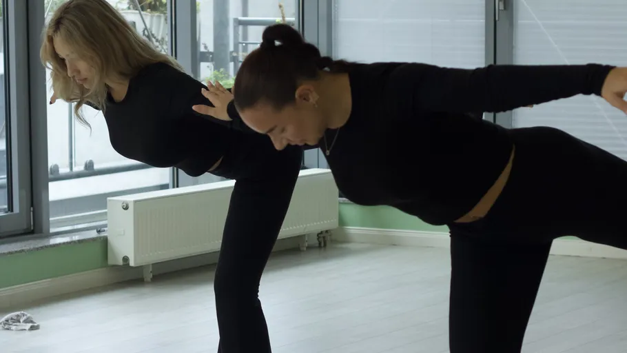 Two women practicing yoga in studio.