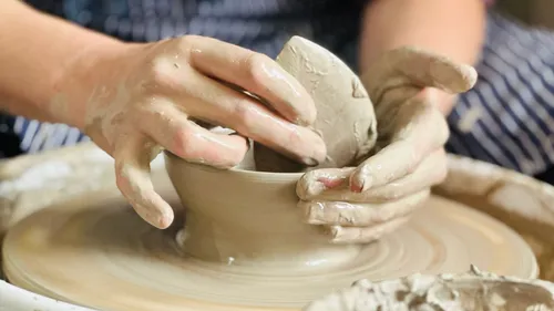 Hands shaping clay on a pottery wheel.