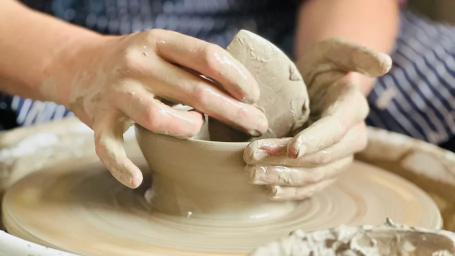 Hands shaping clay on a pottery wheel.