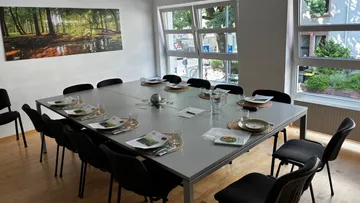 Gedeckter Esstisch mit Stühlen und Fenstern.