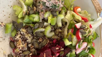 Salat mit Samen, Gemüse und Quinoa auf Teller.