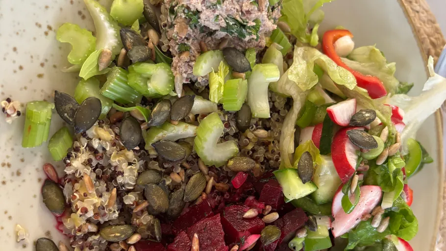Salad with seeds, vegetables, and quinoa on plate.