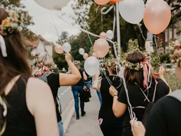 Frauen mit Ballons gehen auf einer Straße spazieren.