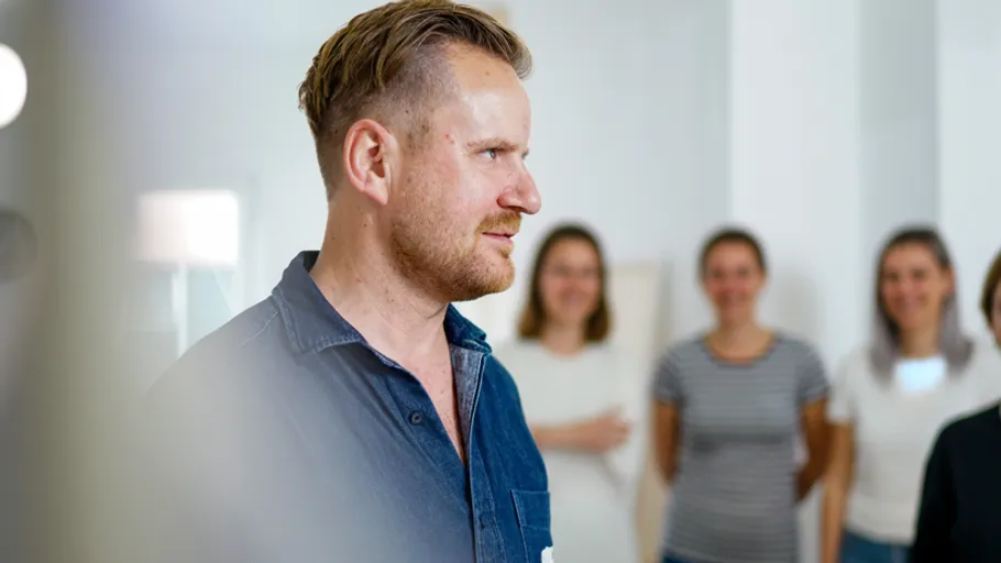 Man standing in front of a group indoors.