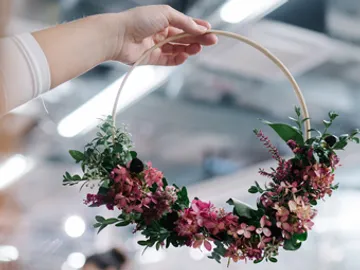 Blumenkranz wird von einer Hand gehalten, helle Umgebung.