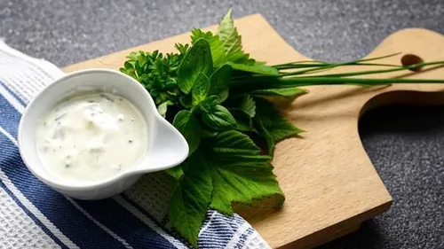 Herbs and dip on wooden board.
