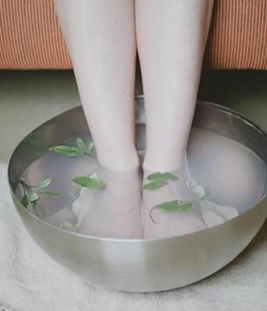 Feet soaking in water bowl with leaves.
