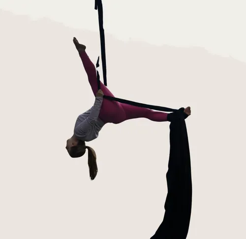 Woman performs aerial silk dance indoors.