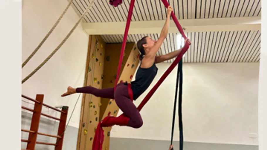 Person performing aerial silk pose indoors.