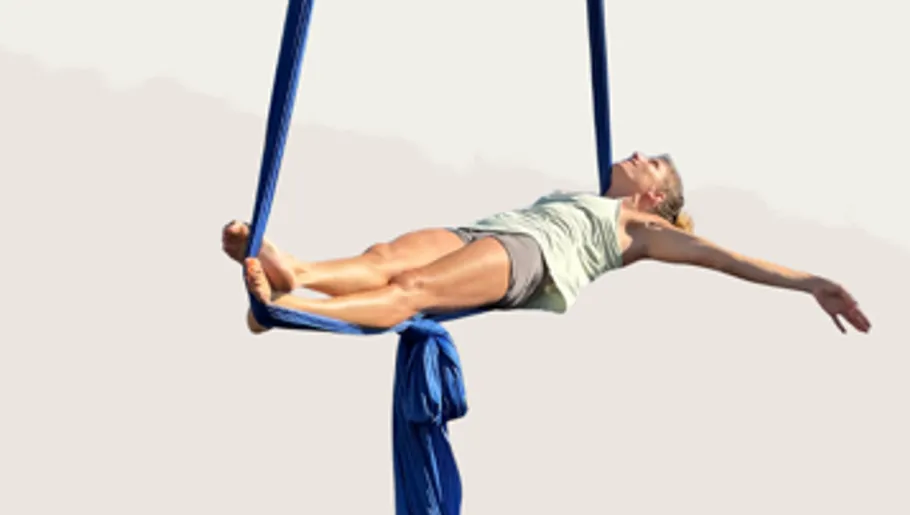 Woman performs aerial silk on blue fabric.