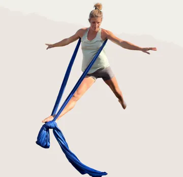 Frau macht Luft-Yoga mit blauem Tuch.