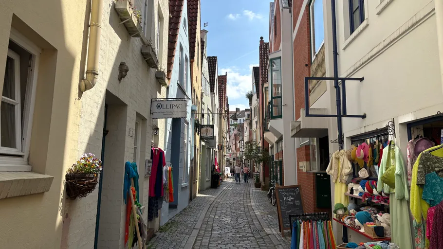 Narrow cobblestone street with colorful shops.