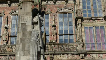 Steinstatue neben verziertem historischem Gebäude.