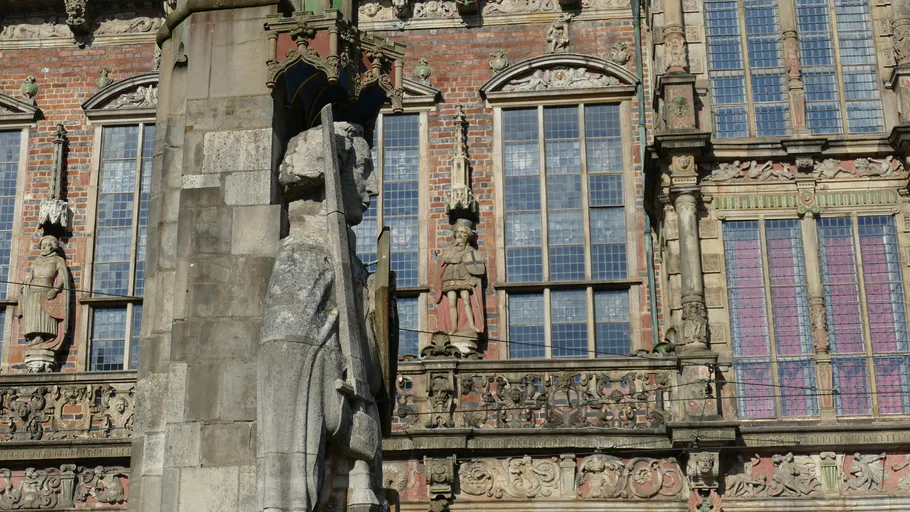 Statue of knight with historic building facade.
